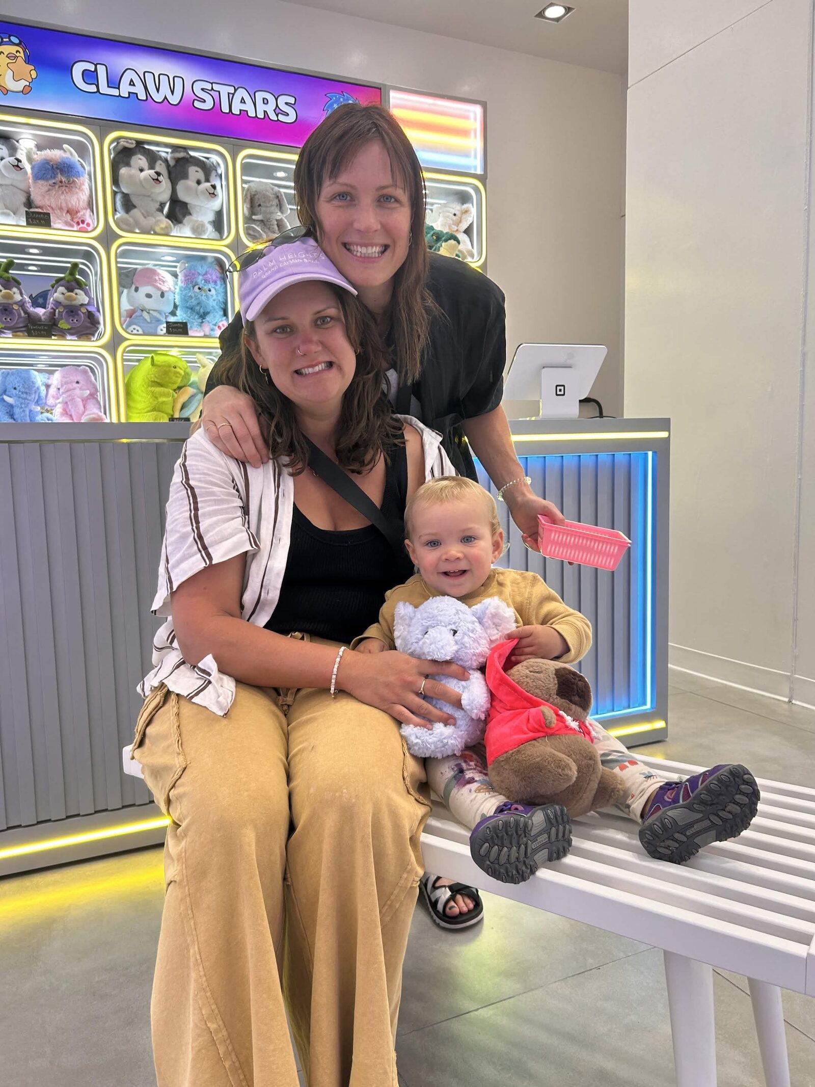 A toddler at the Claw Stars counter holding a freshly won plushie
